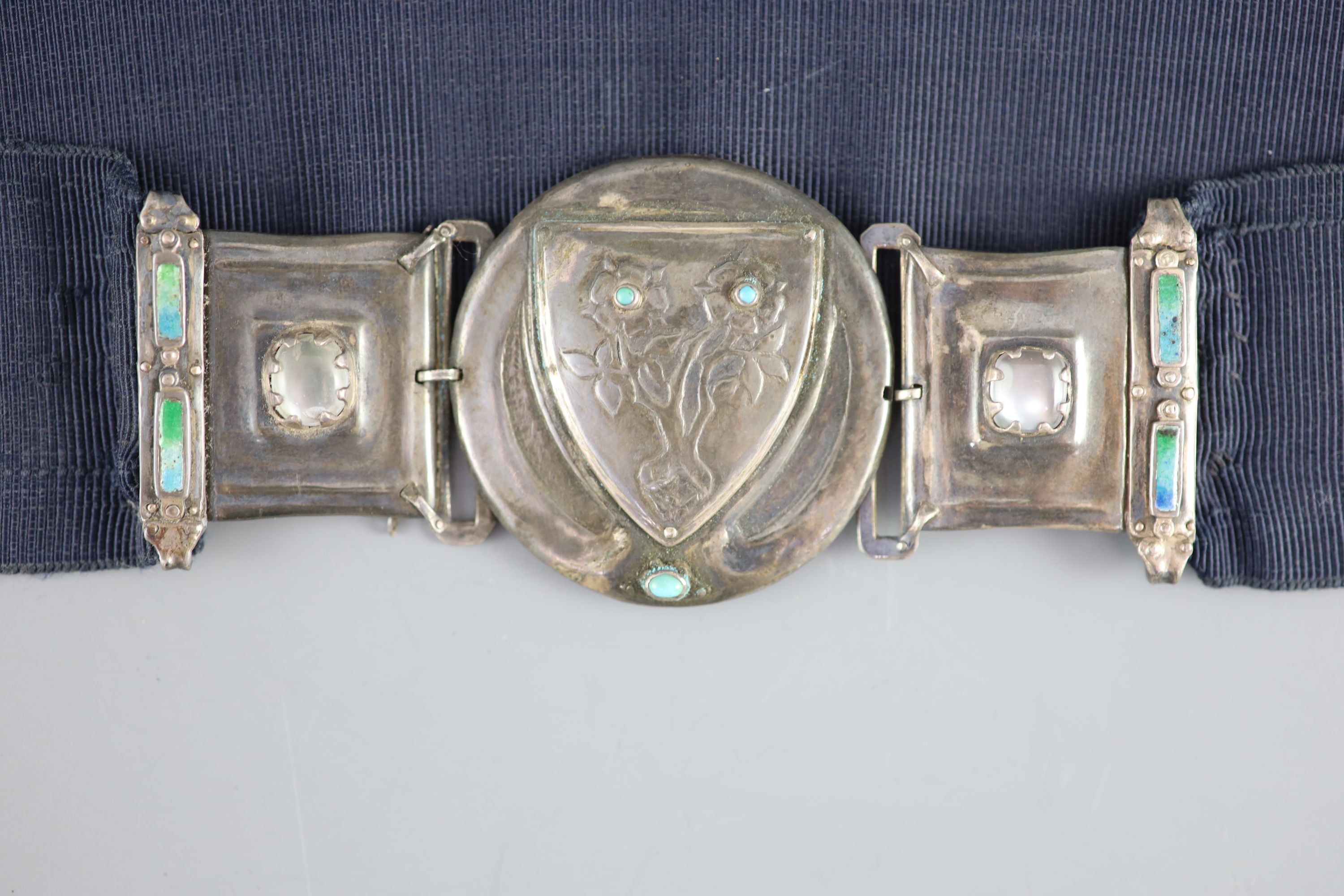 An early 20th century Arts & Crafts silver, enamel, turquoise and cabochon moonstone mounted buckle, on a sash belt